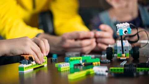 Junge Hände setzen einen Roboter aus Lego zusammen