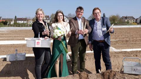 Gruppenfoto von Ministerpräsident Rhein, der Hessischen Spargelkönigin sowie weiteren Personen auf einem Spargelfeld.
