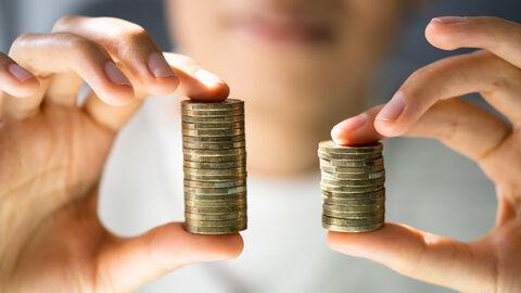 Eine Person hält gestapelte Geldmünzen in beiden Händen nach vorne.