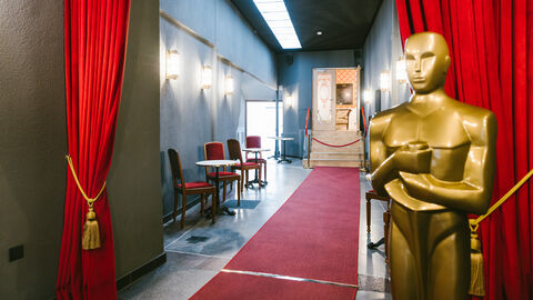 Der Hessische Film- und Kinopreis geht 2022 dort hin, wo der Film hingehört: ins Kino. Eingang der FilmBühne in Bad Nauheim, man sieht einen Gang mit rotem Teppich, lebensgroßer Oscar-Statue und roten Vorhängen