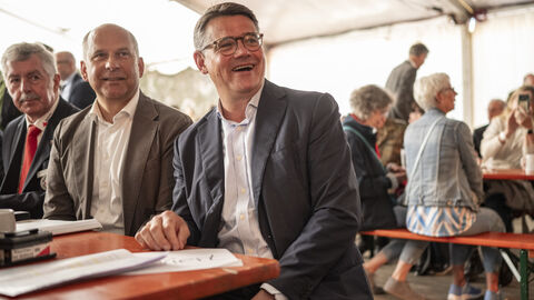 : Ministerpräsident Boris Rhein und Innenminister Roman Poseck sitzen auf Bierbänken beim Tag der ehrenamtlichen Einsatzkräfte